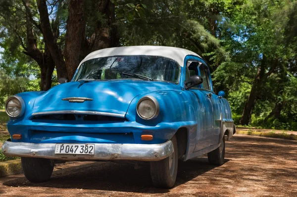 Santa Clara , Cuba - September 04, 2016: Blue american Plymouth classic car with white roof parked under trees in Cuba - Serie Cuba 2016 Reportage