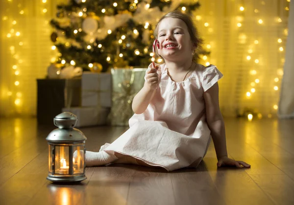Curious little girl smiling, eating christmas candy cane