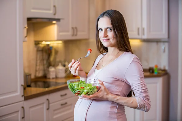 Pregnant woman eating vegetable salad.
