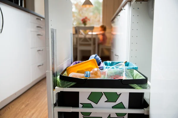 Three trash bins with sorted garbage in kitchen cabinet with segregated household garbage