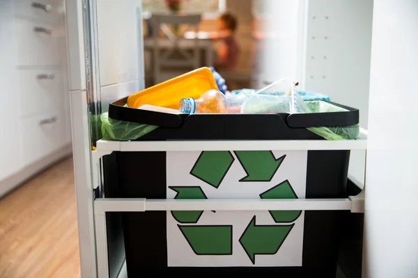 Three trash bins with sorted garbage in kitchen cabinet with segregated household garbage