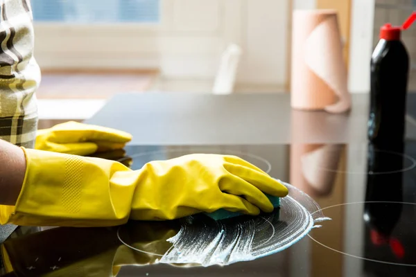 Housewife in rubber protective cleaning and polish electric cooker