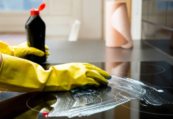 Housewife in rubber protective cleaning and polish electric cooker