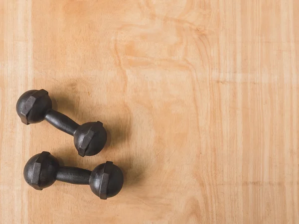 Top view of iron dumbbells or exercise weights on wooden table background. Free space for text
