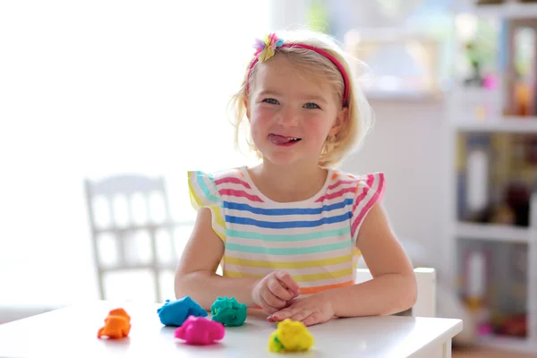 Preschooler girl playing indoors with plasticine