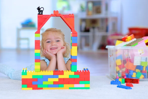 Little girl playing with construction bricks indoors