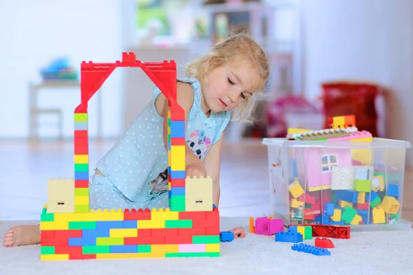 Little girl playing with construction bricks indoors