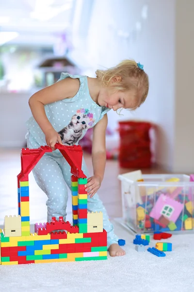 Little girl playing with construction bricks indoors