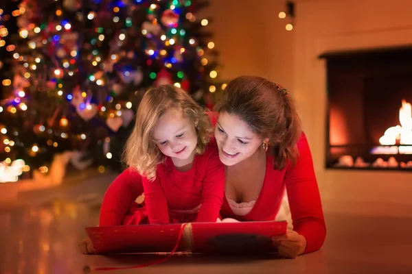 Mother and daughter reading at fire place on Christmas eve