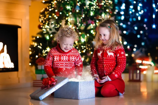 Kids opening Christmas presents at fireplace