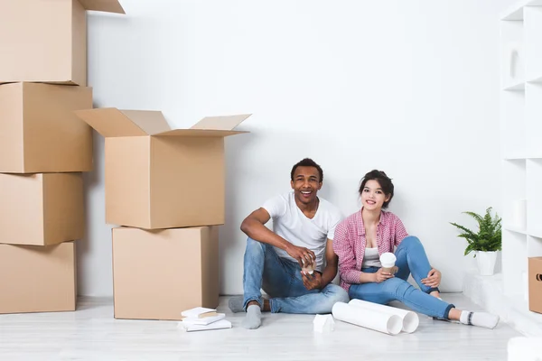 Young couple in a new home relaxing on the background of big boxes.