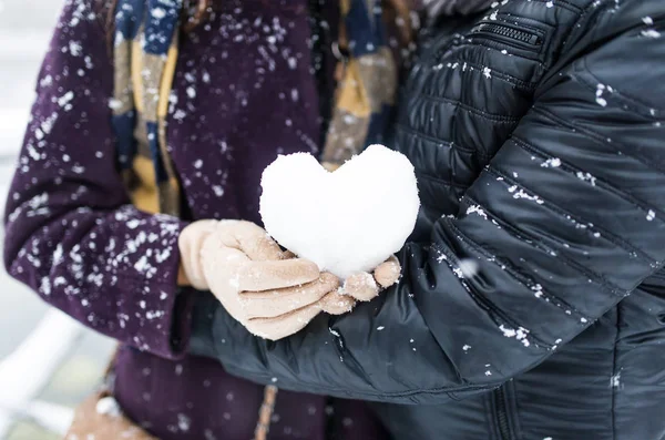 Young couple outside with a heart shape snowball