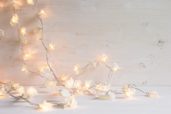 Christmas lights burning  on a white wooden background.