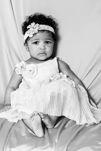 Cute baby girl portrait wearing white floral dress monochrome