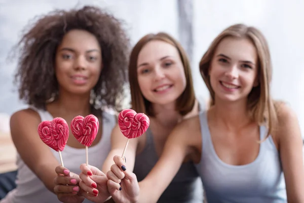 Smiling young girls holding lollipops