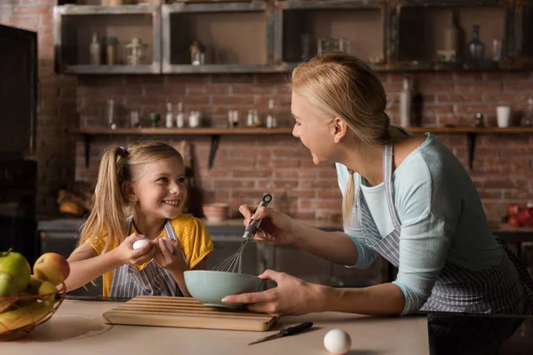 Happy little girl helping her mother in the kitchen