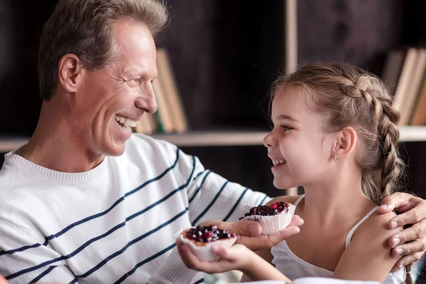 Little girl holding cupcakes with her grandfather