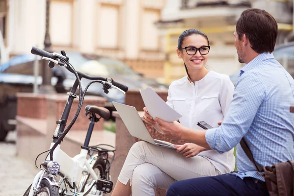 Joyful colleagues sitting in the street