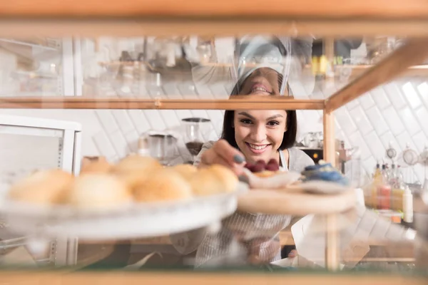 Cheerful pretty smiling woman getting cake from display stand.
