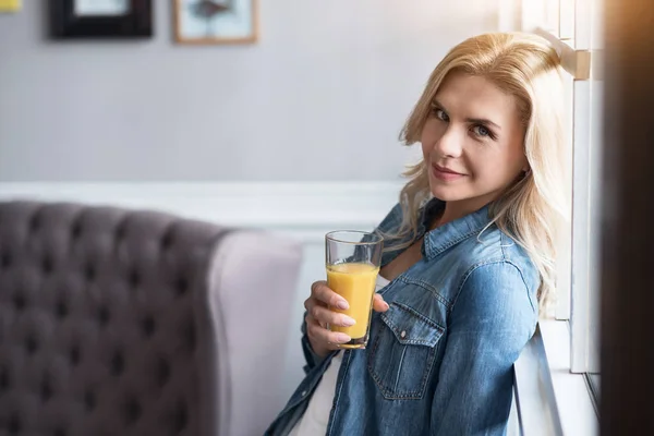 Pretty blond woman with juice at window