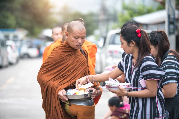 Unidentified women giving food to monks
