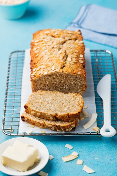 Healthy vegan oat and coconut loaf bread, cake on a cooling rack Blue stone background