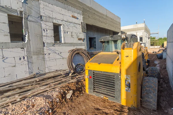 Bulldozer and brick and concrete house under construction