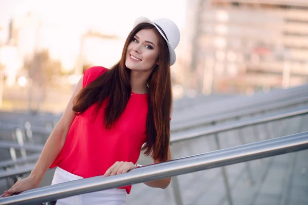 Beautiful young and happy woman in a fashionable hat and beautiful long manicured hair and walks around the city poses. Hipster, fashion, city