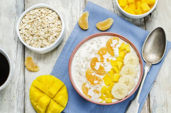 Oatmeal with mango, banana, tangerine oranges and coconut flakes