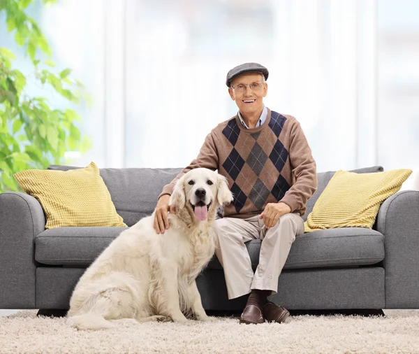 Mature man sitting on sofa and posing with his dog