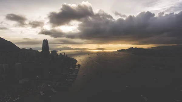Aerial photo from flying drone of a fascinating beauty sky with dramatic clounds with sunset over developed Hong Kong city with skyscrapers buildings near sea with riding yachts in evening time