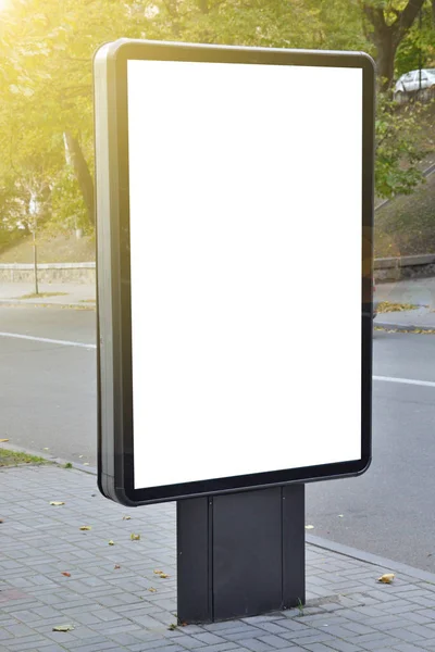 Blank billboard with copy space for your text message or content, outdoors advertising mock up, public information board on city road, flare sun light. Empty Lightbox on urban setting sideline