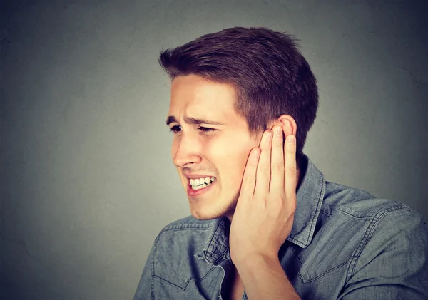 Tinnitus. Sick man having ear pain touching his painful head