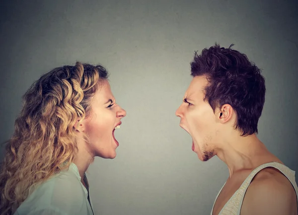 Angry young couple screaming face to face.