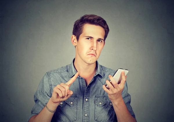 Man with cell phone showing no, don\'t, attention with finger gesture
