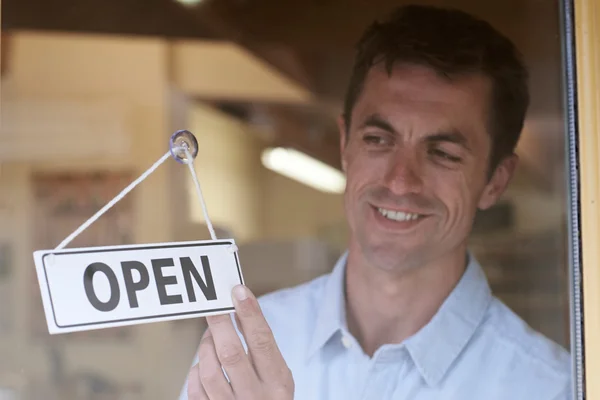 Store Owner Turning Open Sign In Shop Doorway