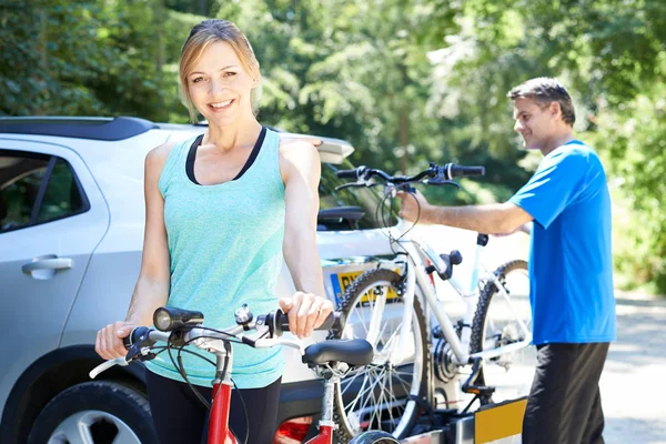 Mature Couple Taking Mountain Bikes From Rack On Car