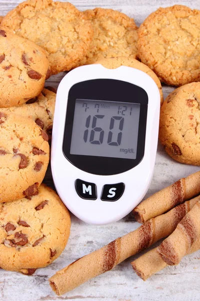Glucometer and heap of cookies, diabetes, reduction eating sweets