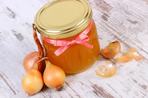 Fresh organic honey in glass jar and onions on wooden background, healthy nutrition and strengthening immunity