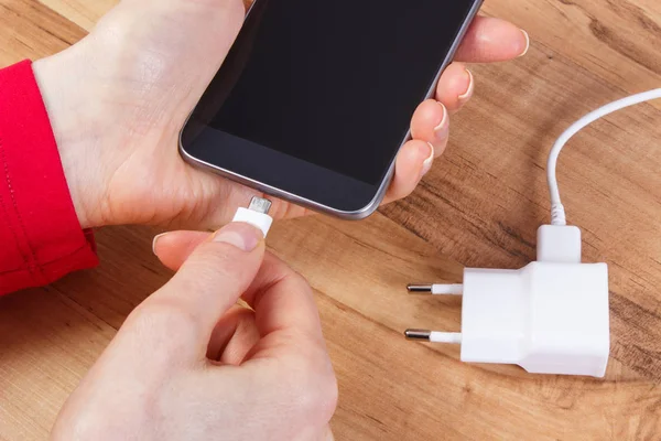 Hand of woman connects plug of charger mobile phone, smartphone charging