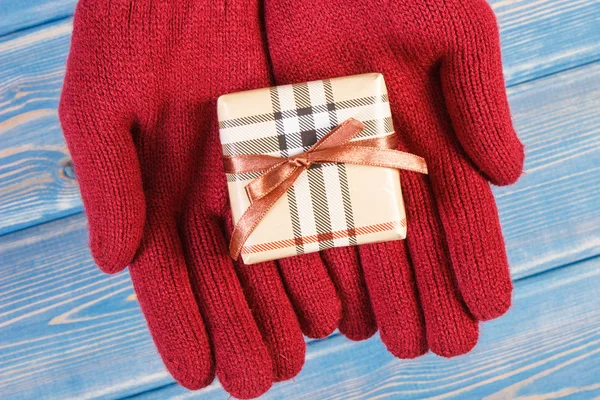 Hands of woman in gloves with gift for Christmas or other celebration