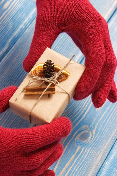 Hands of woman in gloves with decorated gift for Christmas or other celebration