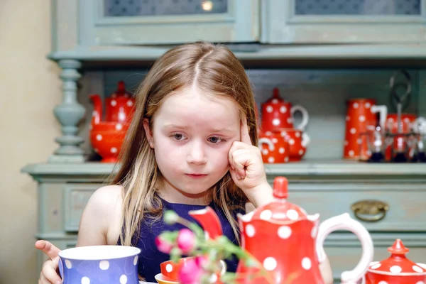 Cute little girl preparing tea in teapot