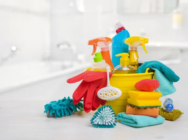 Bucket with chemical products on table over blurred bathroom background