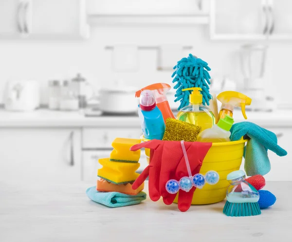 Various colorful cleaning products on table over blurred kitchen background