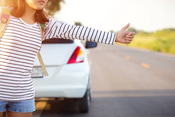Woman hitchhiking looking for help with her broken car on the ro