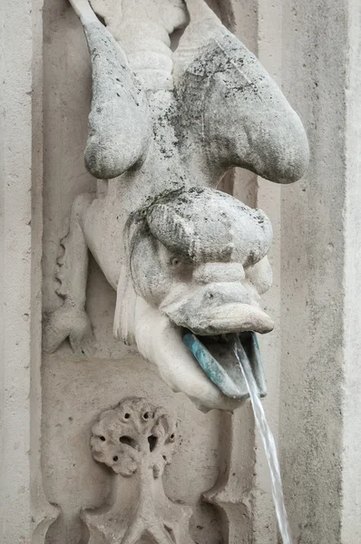 Gargoyle  in a fountain spitting water by mouth