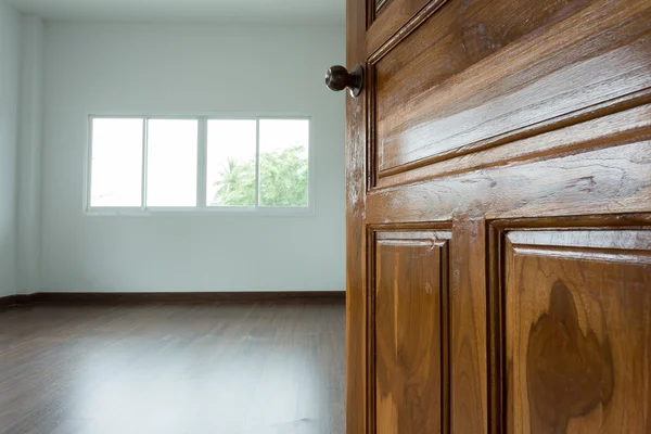 Open wooden door empty white room with window