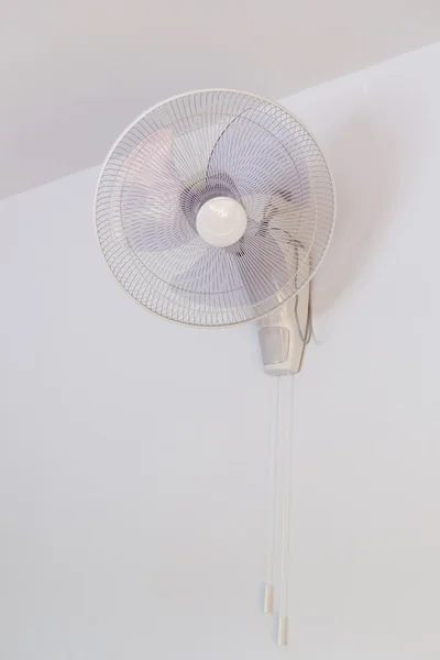 Electric fan hanging on white wall