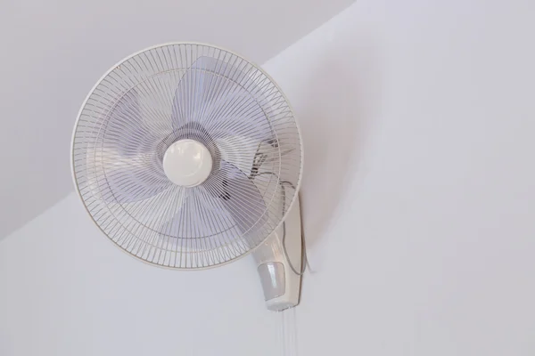 Electric fan hanging on white wall